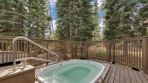 A hot tub on a wooden deck surrounded by a wooden fence, with tall trees in the background. - Ski-In/Ski-Out from this Condo with Shared Hot Tub & Sauna Acces (Breckenridge)