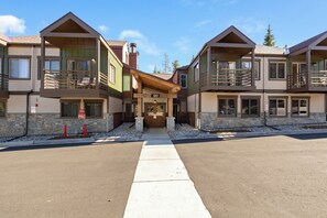 A two-story building with a central entrance, balconies, and a stone facade.