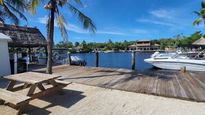 A wooden dock with a picnic table, a boat named 'Hurricane', and a thatched-roof structure. - Hidden gem in Key Largo, bunk room, outdoor kitchen, 2 pools, laundry, 2 beaches (Key Largo)