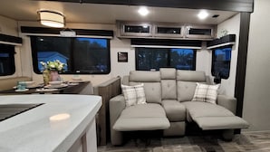 A cozy RV interior with a kitchenette, a seating area with cushions, and a window offering a view of the outside. - Hidden gem in Key Largo, bunk room, outdoor kitchen, 2 pools, laundry, 2 beaches (Key Largo)
