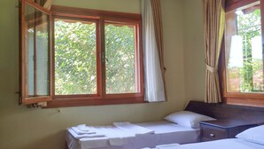 Hotellihuone, jossa on kaksi sänkyä, suuri ikkuna ja kattovalaisin.