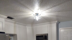 A compact kitchen with white cabinets, a stainless steel refrigerator, a microwave, a stove, and a dishwasher. - Great location.  Ten minutes from  Beach.  Peaceful retreat! (Merritt Island)