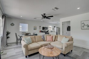 Una sala de estar moderna con un sofá color beige, una mesa de centro de madera y un ventilador de techo.