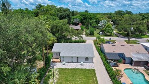 A residential property with a large lawn, a swimming pool, and a covered patio area.