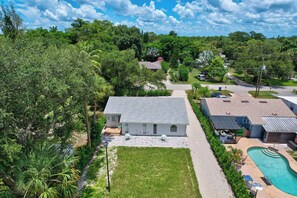 A residential property with a large lawn, a swimming pool, and a covered patio area.