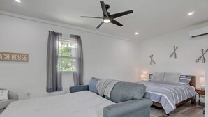 Une chambre avec deux lits, un ventilateur de plafond et une fenêtre avec des rideaux.