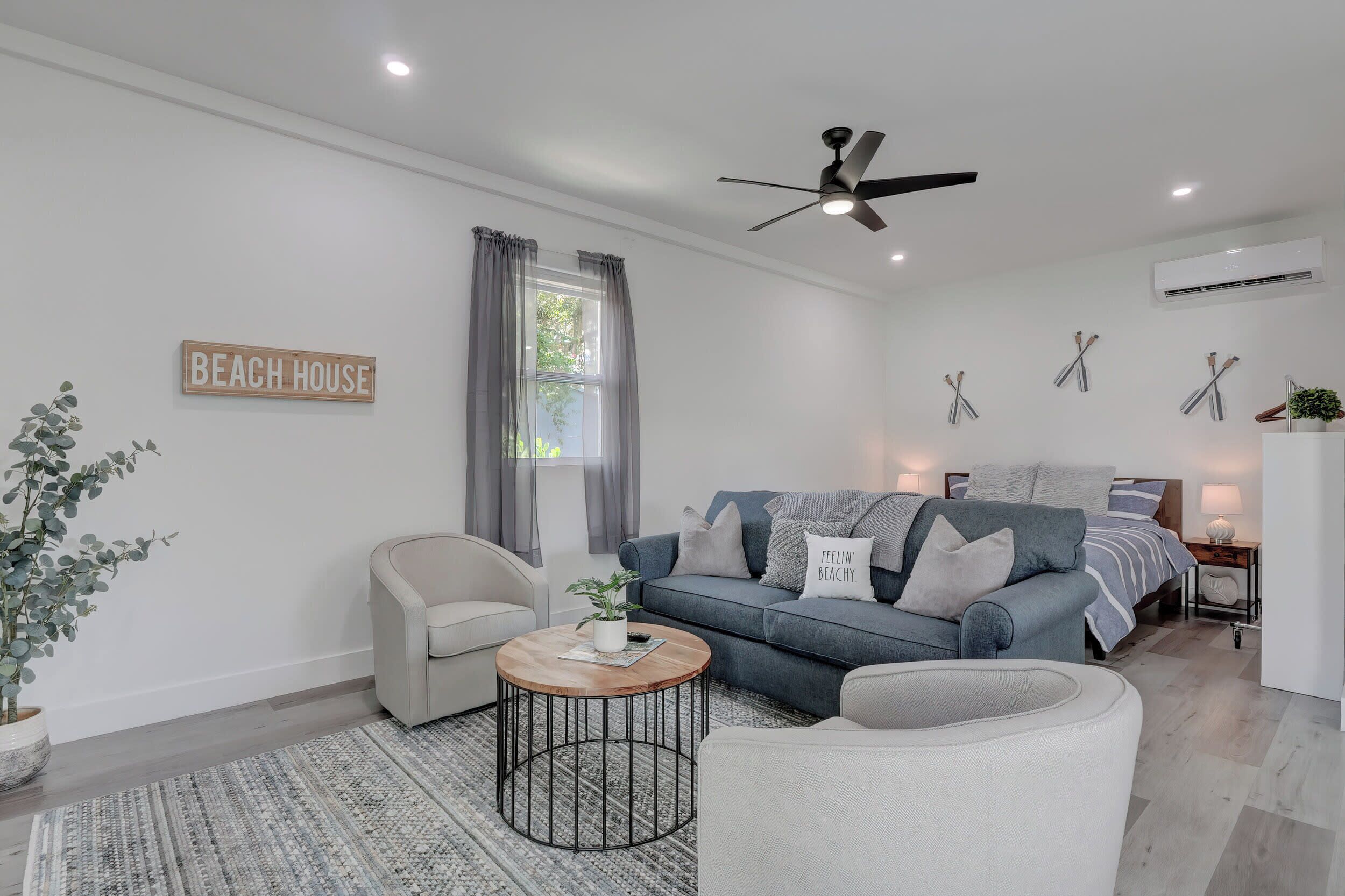 Un salon moderne comprenant un canapé, un fauteuil, une table basse et un ventilateur de plafond.