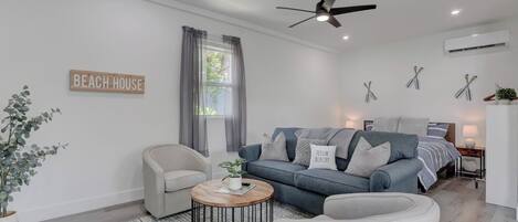 Un salon moderne comprenant un canapé, un fauteuil, une table basse et un ventilateur de plafond.