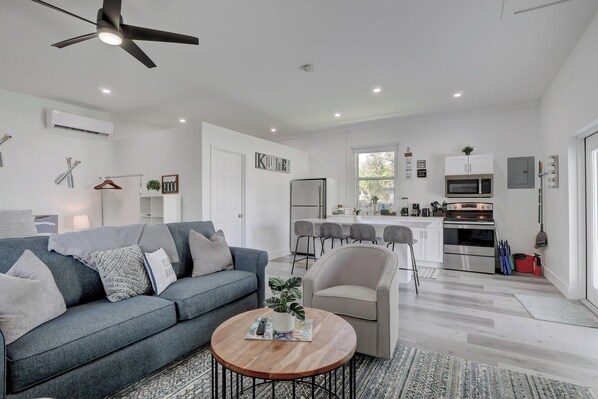 A modern living room with a grey sofa, a round coffee table, and a ceiling fan.