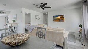 Un soggiorno moderno con un divano, un tavolo da pranzo e una ventola a soffitto.