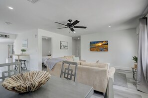 Una sala moderna con un sofá, una mesa de comedor y un ventilador de techo.