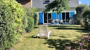Una casa con un porche techado, césped y una silla.