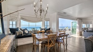 Un'ampia zona giorno con un tavolo da pranzo in legno, posti a sedere confortevoli e ampie finestre vista mare.