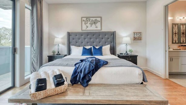 Ein Schlafzimmer mit einem großen Bett, zwei Nachttischen, einer Weltkarte an der Wand und Blick ins Freie.