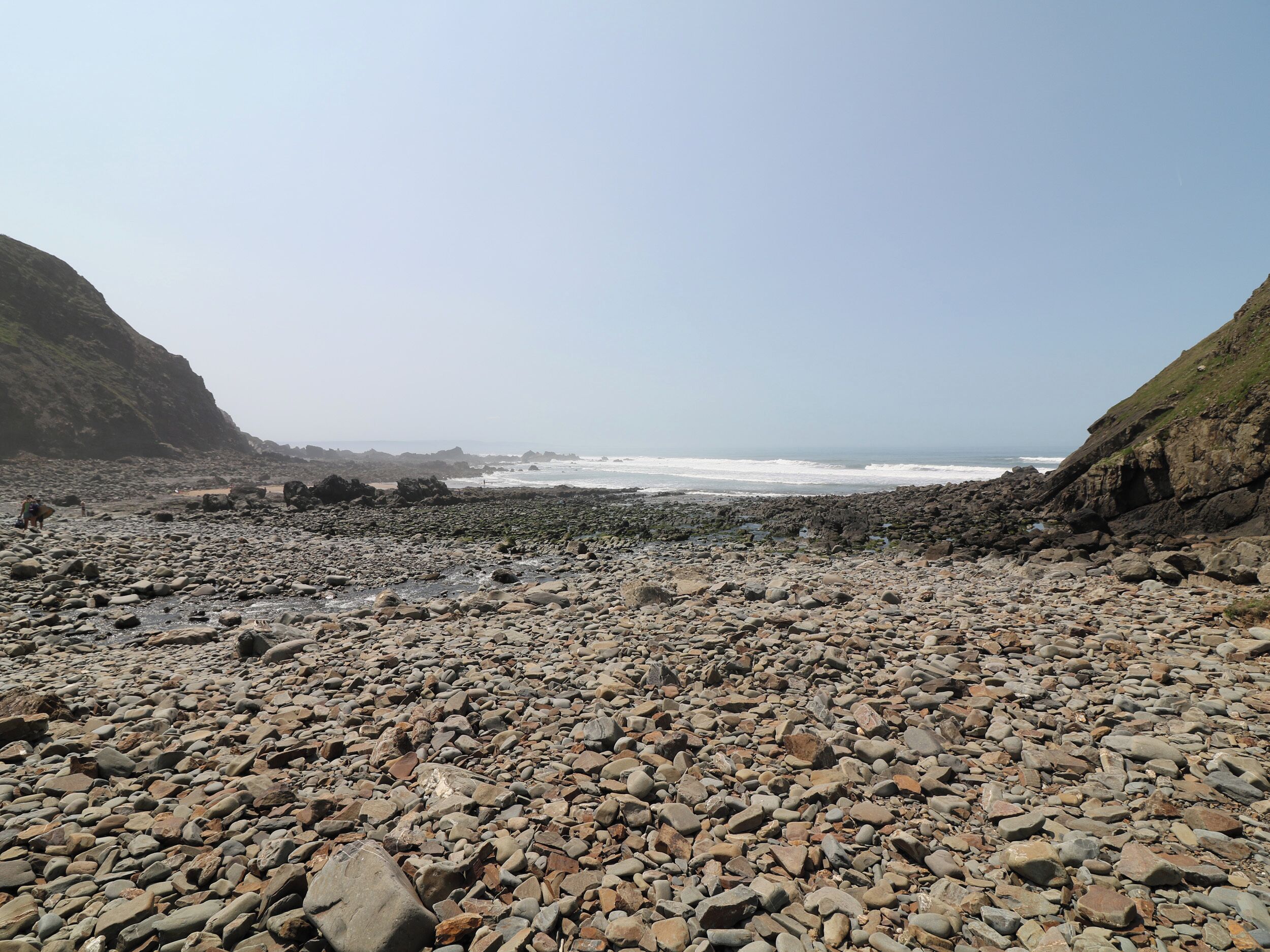 Ein felsiger Strand mit brechenden Wellen, umgeben von Klippen.