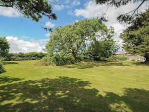 A grassy field with trees and a stone building.