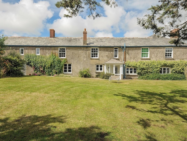 A two-story stone building with a well-maintained lawn in front.