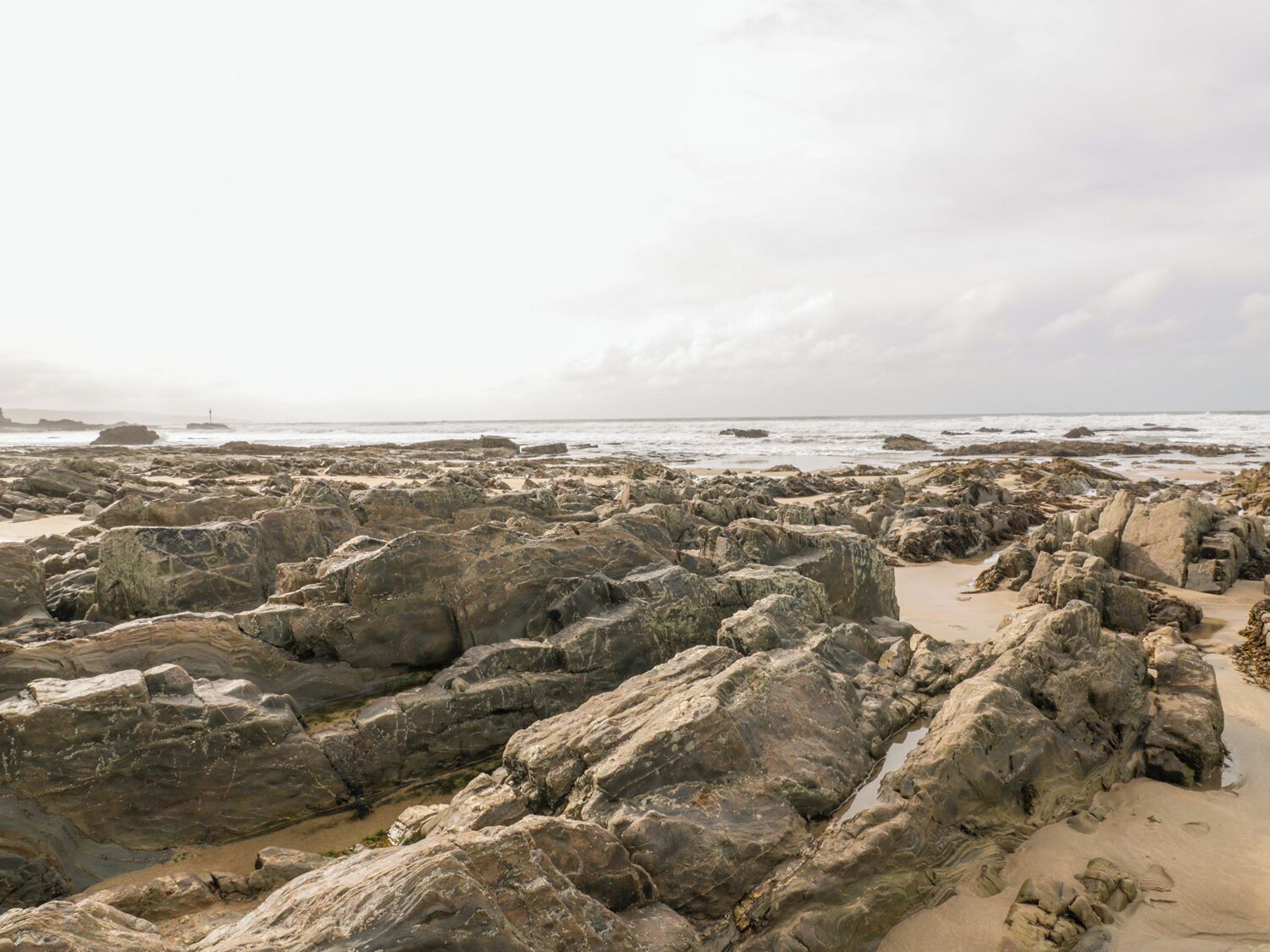 A rocky beach with large boulders and a sandy area.