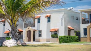 A two-story building with a white facade, red-tiled roof, and a security camera. - Gated Beachfront House - 10 Minutes from Kingston (Portmore)