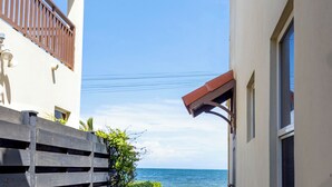 A narrow pathway leading to a balcony with a view of the sea. - Gated Beachfront House - 10 Minutes from Kingston (Portmore)