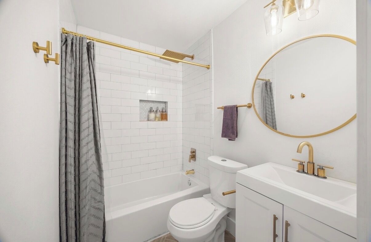 A bathroom with a bathtub, toilet, sink, and a large mirror.