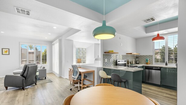 Une cuisine moderne dotée d’un îlot central, un coin repas avec une table et des chaises en bois, et un espace de vie comprenant un canapé et un bureau.