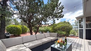 Un patio exterior con un sofá modular, una mesa de centro de vidrio y una botella de champán.