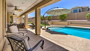 Un patio couvert avec une piscine, du mobilier d’extérieur et des ventilateurs de plafond.