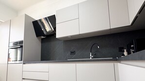 Une cuisine moderne avec des armoires blanches, un comptoir noir et un four encastré.