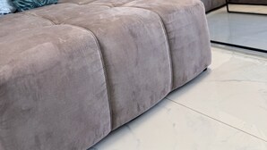 Un salon moderne avec un canapé d’angle gris, une petite table sur laquelle est posée une plante, et une œuvre d’art abstraite accrochée au mur.