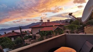Un balcon avec une table et des chaises, donnant sur un quartier résidentiel avec des maisons et un plan d’eau.