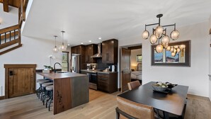 A modern kitchen with a central island, wooden bar stools, and pendant lighting. - Estes Dream! End Unit with Patio, Indoor/Outdoor Fireplace and Jacuzzi (Estes Park)