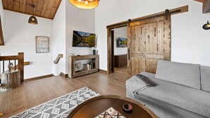 A cozy living room with a wooden ceiling, a gray sofa, a wooden coffee table, and a fireplace with a rustic mantel. - Estes Dream! End Unit with Patio, Indoor/Outdoor Fireplace and Jacuzzi (Estes Park)