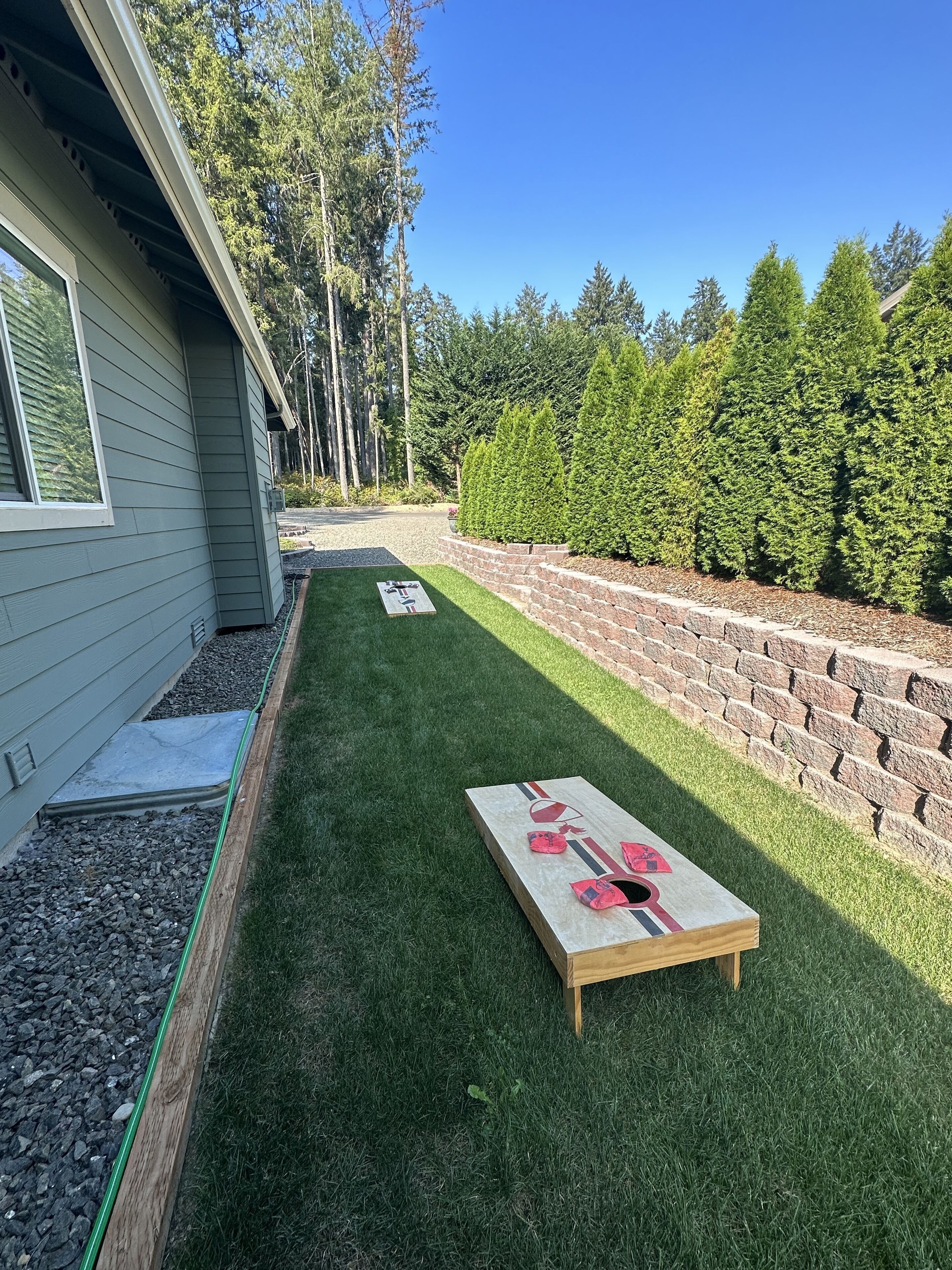 Une pelouse bien entretenue, avec une table de jeu de palet et un mur en briques.