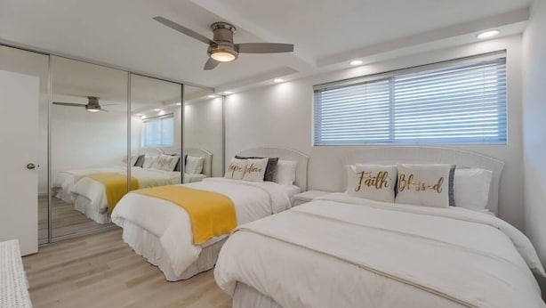 A hotel room with two beds, a ceiling fan, a large mirror, and a window with blinds. - Modern 1bd Oceanfront view with parking and pool (San Diego)