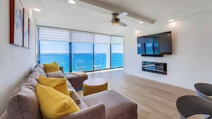 A modern living room with a sofa, chairs, a TV, and a view of the ocean. - Modern 1bd Oceanfront view with parking and pool (San Diego)