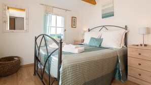 A bedroom with a bed, a wooden dresser, a nightstand, a mirror, and a window with curtains. - Les Villas de Fontenelles (Apremont)