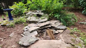 A garden with a stone wall, a blue birdbath, and various plants. - TREETOPS house! AUG openings! A Reunion/Retreat estate! Seasonal POOL! Sleeps 12 (Guilford)