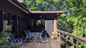 A wooden deck with a glass door leading to a covered patio area. - TREETOPS house! AUG openings! A Reunion/Retreat estate! Seasonal POOL! Sleeps 12 (Guilford)