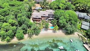 An aerial view of a resort with multiple buildings, a beach, and clear waters.