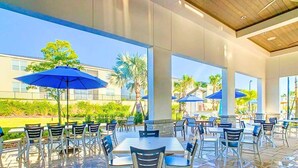 An outdoor patio area with tables and chairs, umbrellas, and a view of the surrounding landscape.