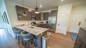 Una cocina moderna con armarios de madera oscura, electrodomésticos de acero inoxidable y una encimera de granito.