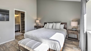 A bedroom with a large bed, bedside tables with lamps, a bench, and a walk-in closet. - Modern Flagstaff Retreat ~ 4 Mi to Downtown! (Flagstaff)