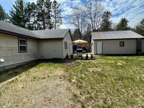 A row of mobile homes with a grassy yard and trees in the background.