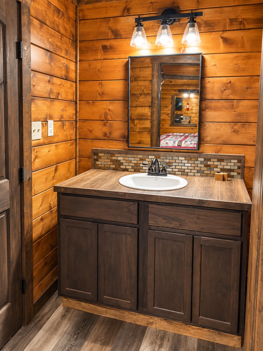 A bathroom with wooden panel walls, a large mirror, a sink with a tiled backsplash, and a wooden vanity.