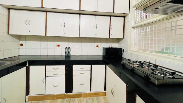 Cucina con mobili bianchi, piano di lavoro nero e fornello a gas.