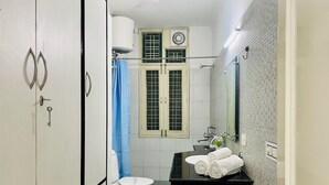 A bathroom with a toilet, sink, and mirror. - BluO 1BHK - DLF Galleria | Balcony, Suite (Gurugram)