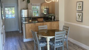 Een moderne keuken met houten kastjes, een roestvrijstalen koelkast en een glazen eettafel met stoelen.