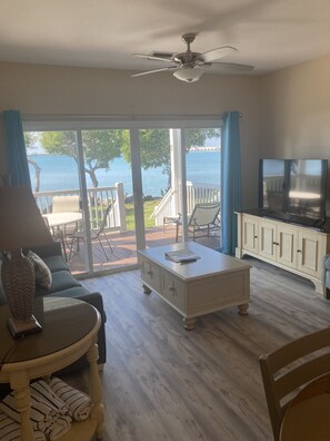 A living room with a view of the sea, a ceiling fan, a TV, and a dining area with outdoor seating. - Villa 5034 on Duck Key Boat Slip Available - 2BD 2.5BA (Duck Key)