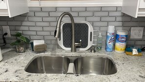 A kitchen with a stainless steel sink, a dish rack, and various cleaning supplies on the countertop. - Penthouse Suite—Steps from Mayo Clinic Hospital (Rochester)